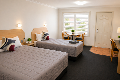 Twin bedroom with two single beds, wooden headboards, and shuttered windows